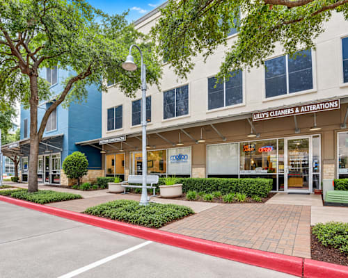 A cleaning and alterations storefront with a red curb in front.