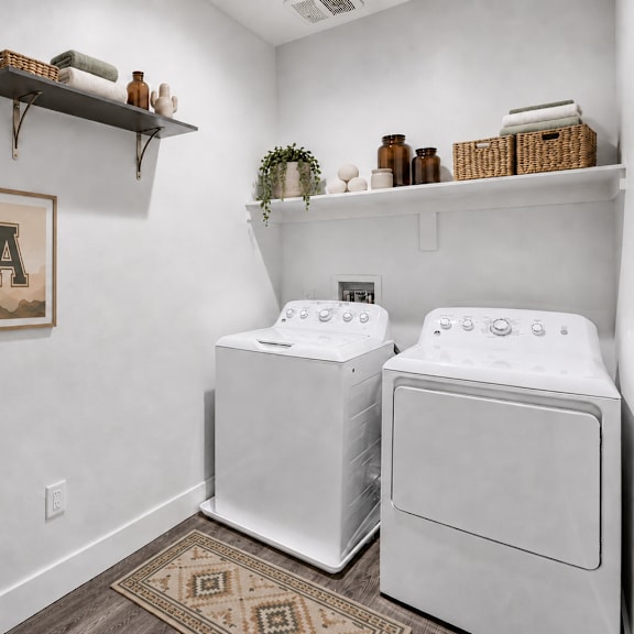 A laundry room with a washer and dryer, a basket, and two framed pictures on the wall.
