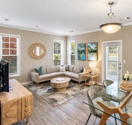 A living room with a glass table and a grey sofa.