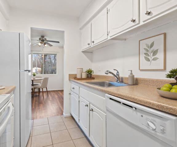 A white kitchen with a refrigerator, sink, and cabinets.