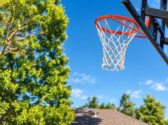 A basketball hoop with a net is seen against a blue sky.