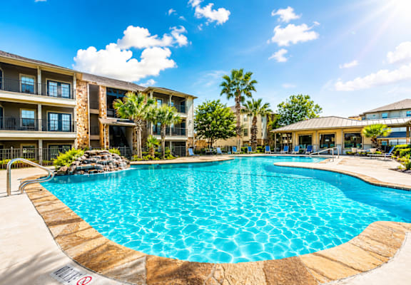 A large swimming pool in front of a resort building.