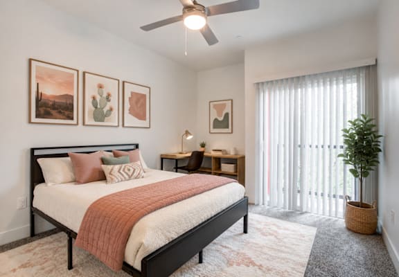 A bedroom with a bed, a ceiling fan, and a plant.