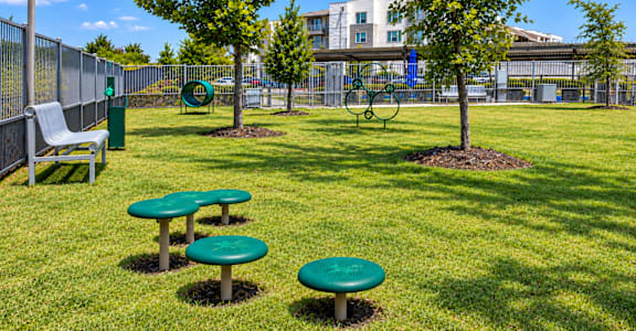 A sunny day at the park with green tables and a bench.