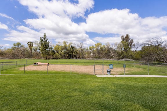 A baseball field with a fence and a sign in the distance.