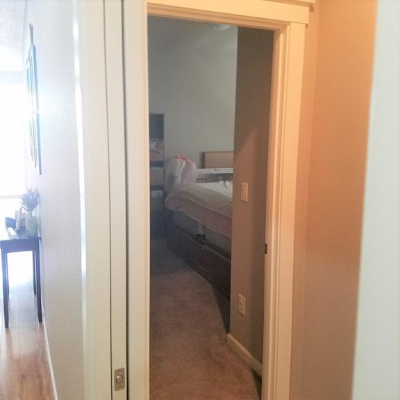 a doorway into a bedroom with a bed and a nightstand