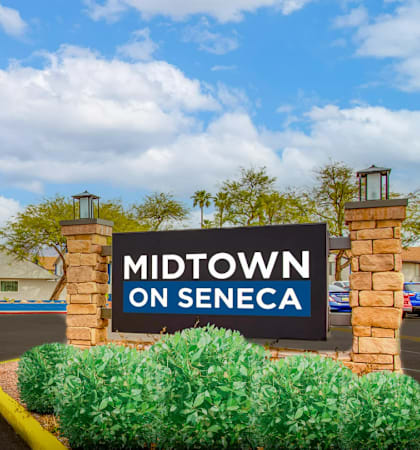 The image shows a sign that reads "Midtown on Seneca" in front of a building with palm trees in the background.