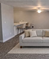 A living room with a couch, a rug, and a table with chairs.