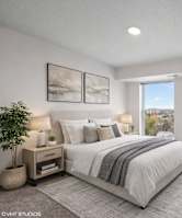 A bedroom with a large bed, a window with a view, and a nightstand with a plant on it.