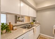 Thumbnail 9 of 11 - A kitchen with white cabinets and a granite countertop at Lifestyle at Shreveport in Shreveport, LA, 71109.