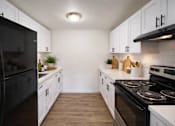 Thumbnail 3 of 8 - A kitchen with black appliances and white cabinets.