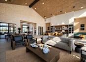 Thumbnail 37 of 47 - Spacious apartment resident lounge with high ceilings, comfortable seating, kitchen island, dining table, and natural light.