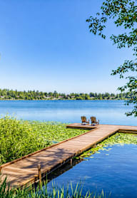 A wooden dock extends into a lake with a bench on it.