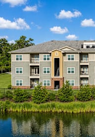 A large apartment complex with a pond in front.