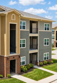 Apartment complex with grey and beige buildings and green lawns.