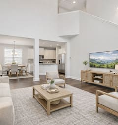 A living room with a white couch, a wooden coffee table, and a television on a wooden stand.