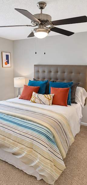 A bedroom with a bed, a ceiling fan, and two lamps.
