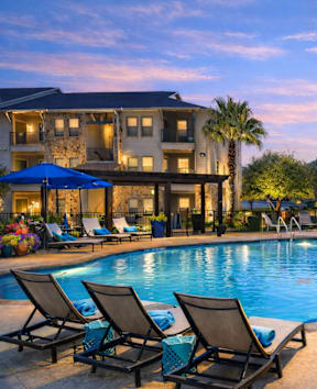 A patio with a blue cushioned sofa and wooden chairs.