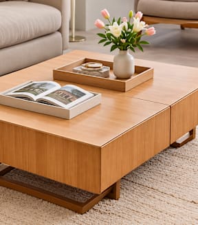 A coffee table with a book and a vase of flowers on it.