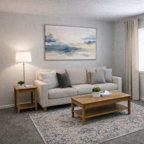 A living room with a white sofa, a wooden coffee table, and a painting on the wall.