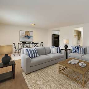 A living room with a grey couch, a white table, and a large window.
