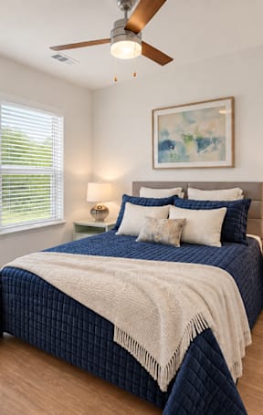 A bedroom with a bed, a dresser, and a ceiling fan.