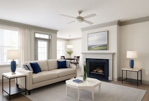 A living room with a white couch, a fireplace, and a painting on the wall.