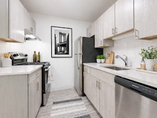 A kitchen with white cabinets and a black fridge.