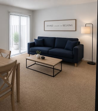 A living room with a wooden table and chairs, a blue couch, and a sign that says "Home is where you belong."