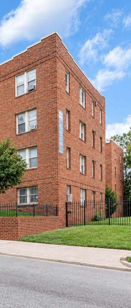 A red brick building with a black fence in front.