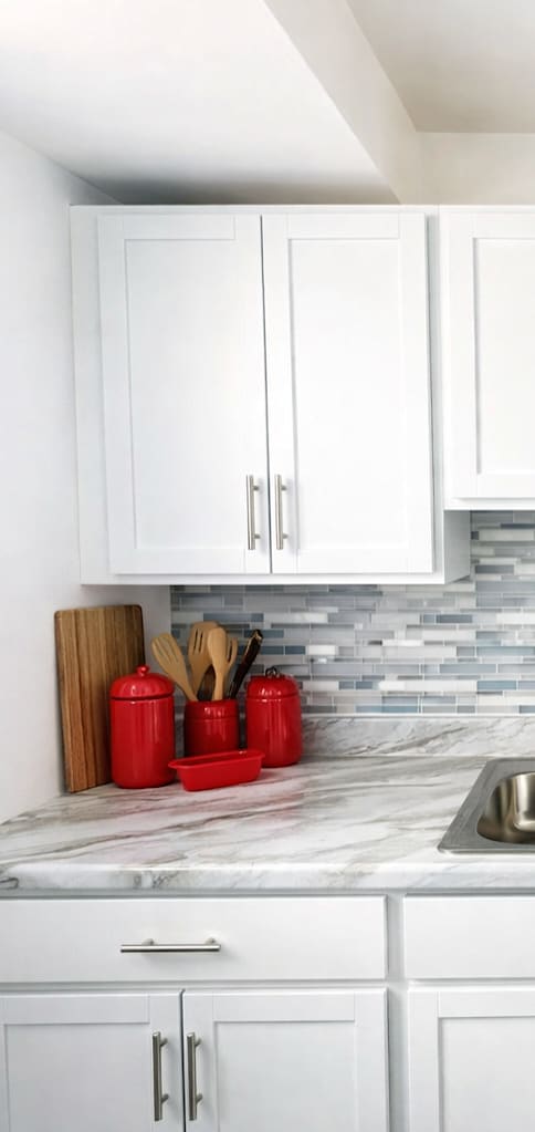 A kitchen with white cabinets and a marble countertop.