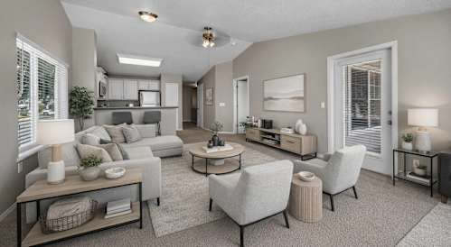 A well-lit living room with a grey sofa set and a coffee table.