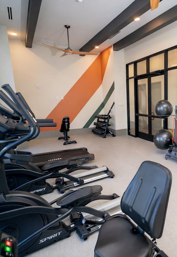 A gym with orange walls and a variety of equipment.