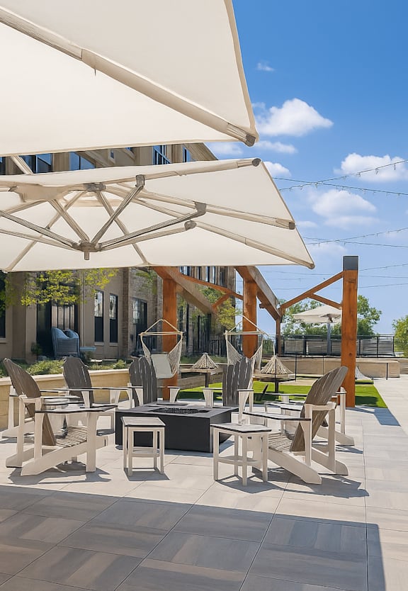 A patio with a grill and chairs under a white umbrella.