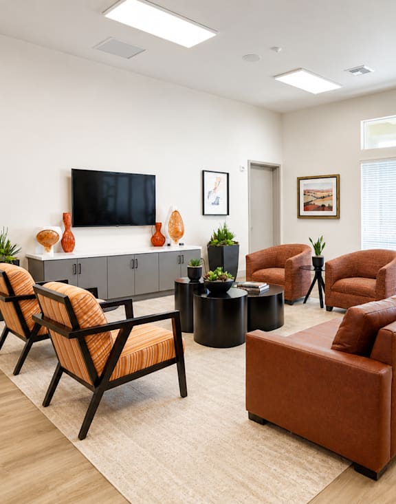 A waiting room with a brown couch and orange chairs.