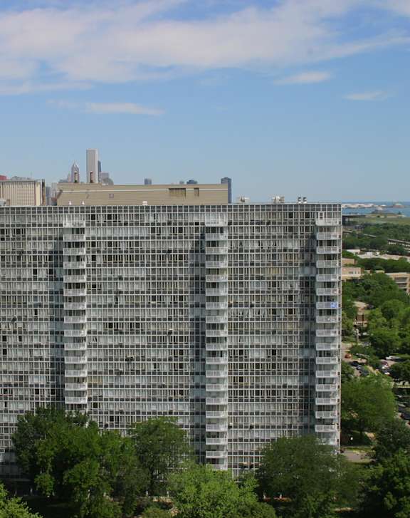 A large building with a lot of windows in the foreground with a city in the background.