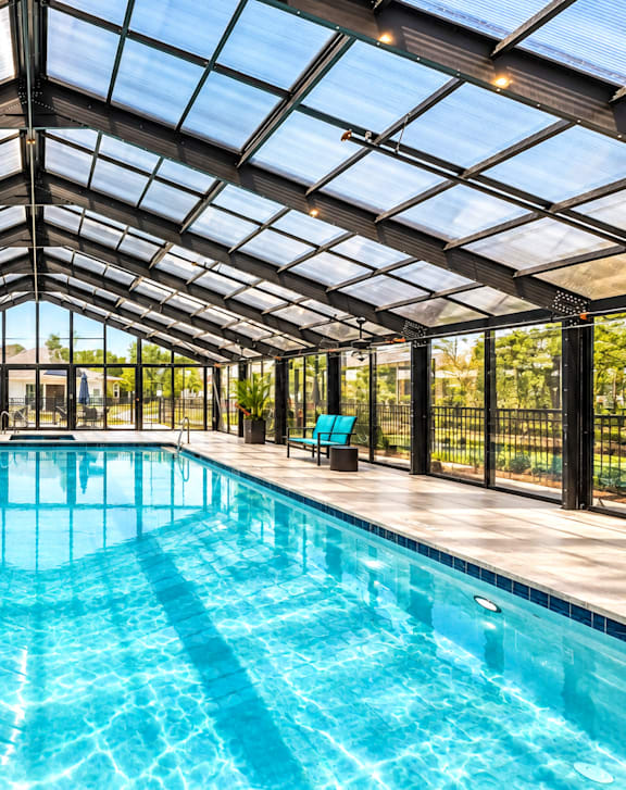 A large indoor swimming pool with a glass ceiling and a diving board.
