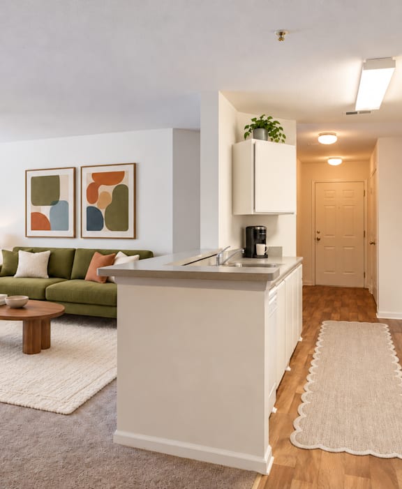 A kitchen with a refrigerator, sink, and a dining table with chairs.