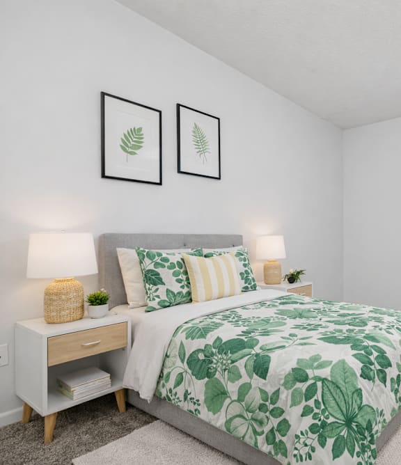 A bedroom with a bed, nightstand, chair, and a window.