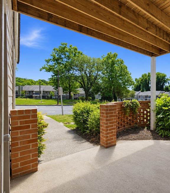 A patio with a wooden roof and brick pillars.