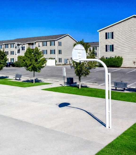 A basketball court in front of apartment buildings.