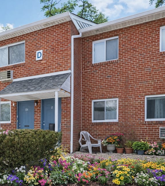 A red brick house with a blue door and a small garden in front.