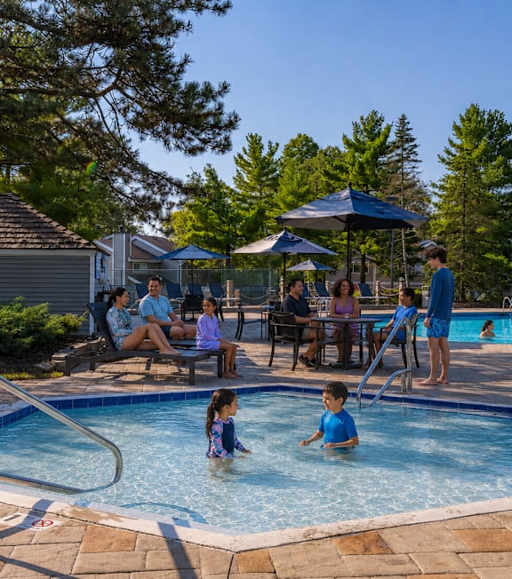 A group of people are enjoying a sunny day at a poolside.