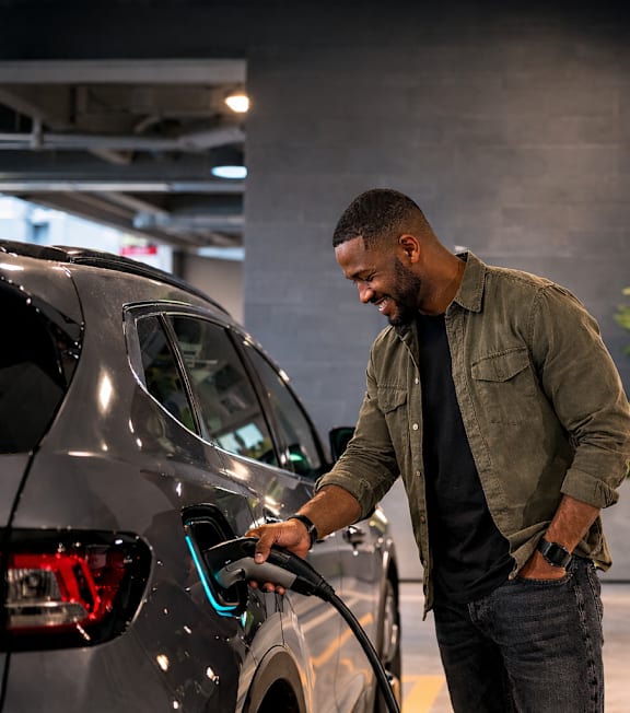 A man charging an electric car at a charging station.
