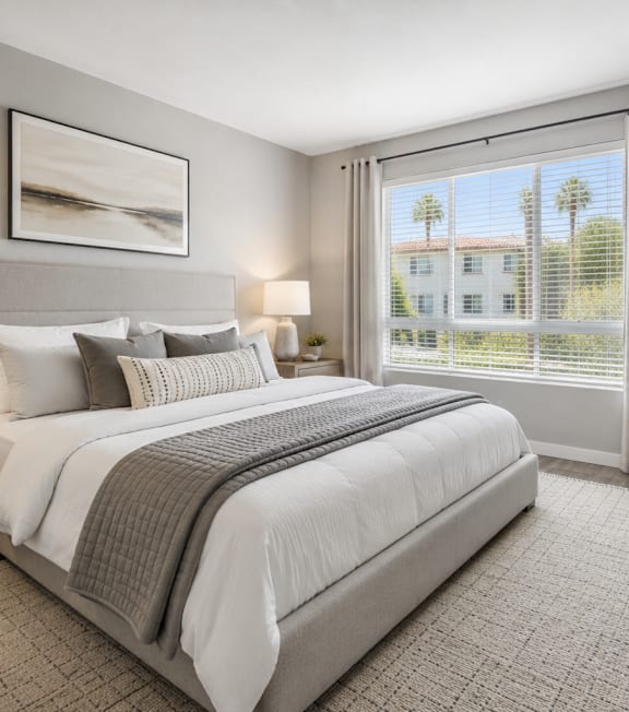 A well-lit bedroom with a large bed, two lamps, and a framed picture on the wall.