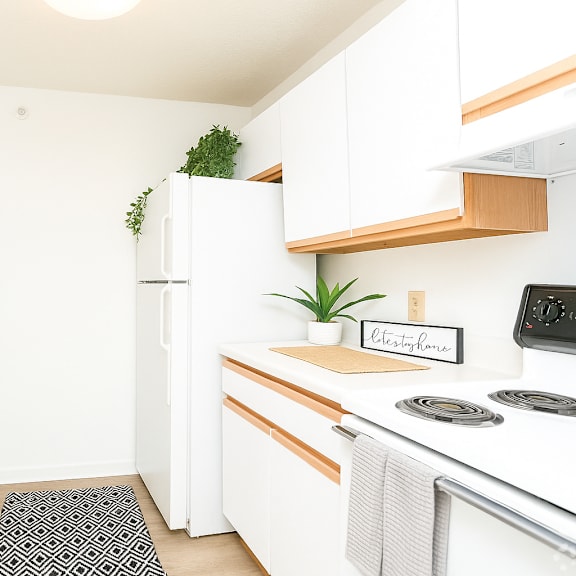 A kitchen with white cabinets and a white fridge.