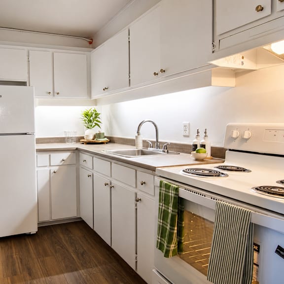 A white kitchen with a refrigerator, sink, and stove.