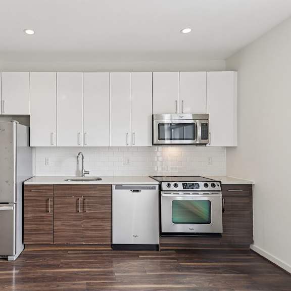 A modern kitchen with a stainless steel refrigerator, microwave, dishwasher, and oven.