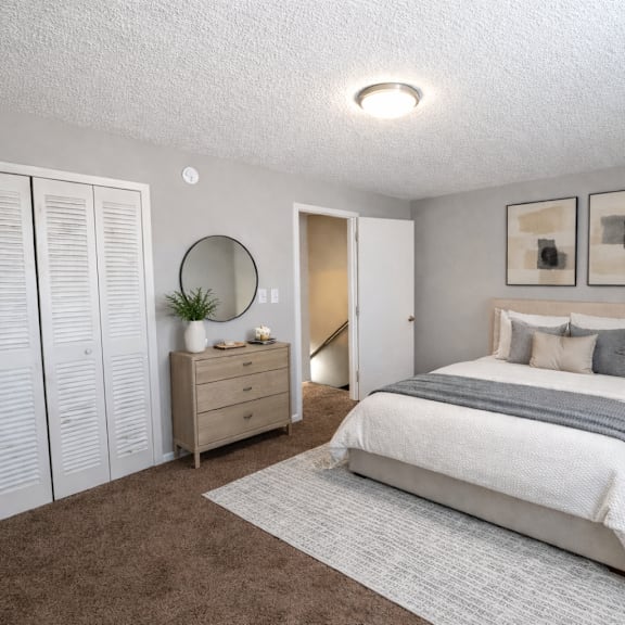 A bedroom with a large bed, a dresser, and a mirror.