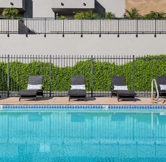A pool with chairs and a fence.